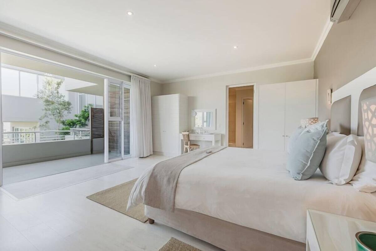 Une chambre moderne avec un grand lit, un bureau et un balcon.