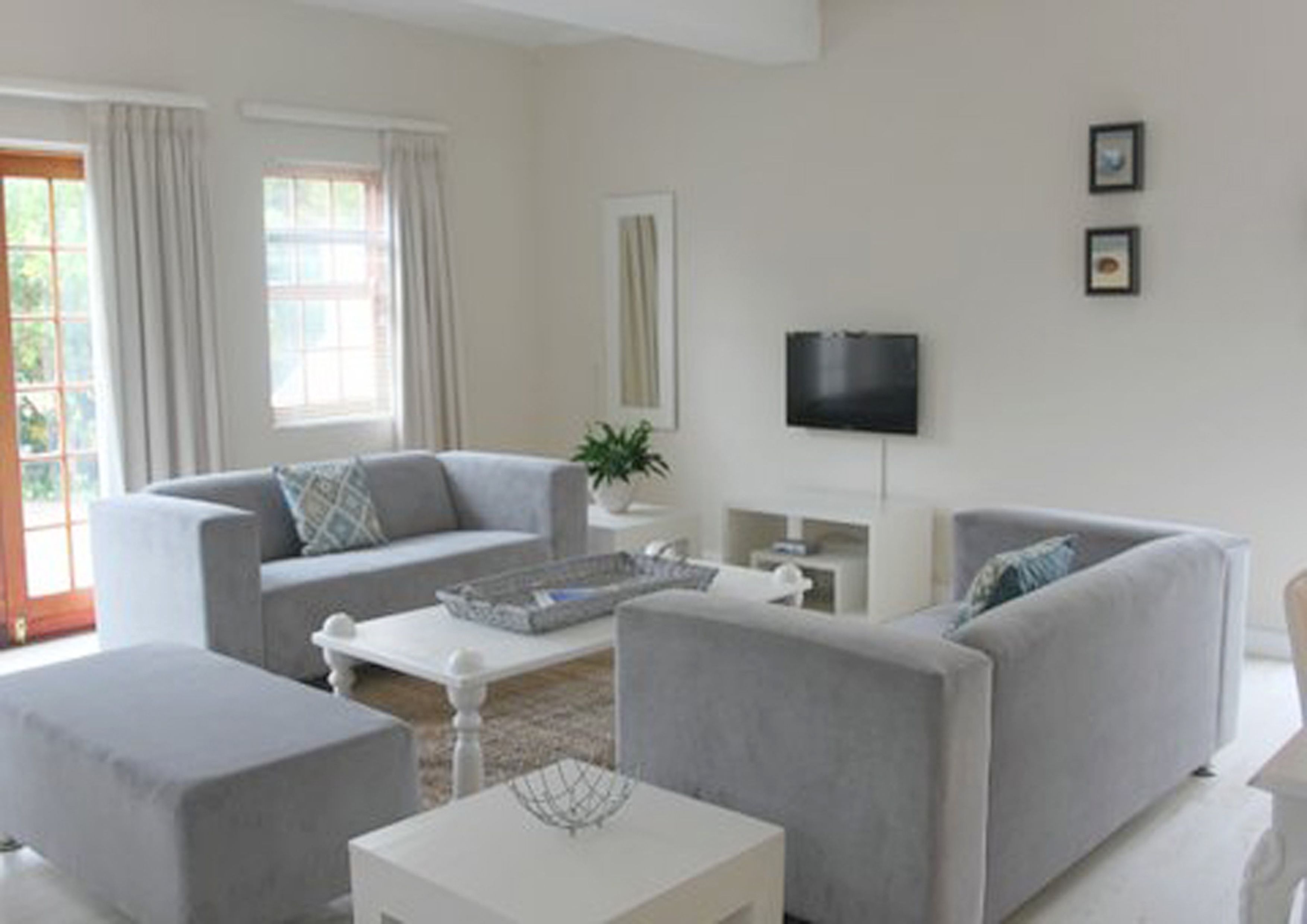 Ein modernes Wohnzimmer mit grauem Sofa, weißem Couchtisch und Wandfernseher.