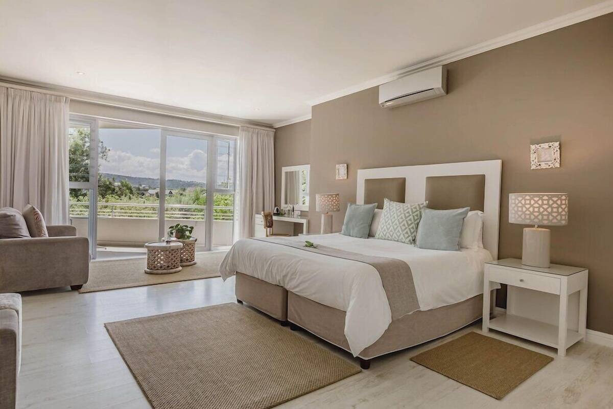 Une chambre avec un grand lit, une table de chevet, une chaise et une vue sur l’extérieur.