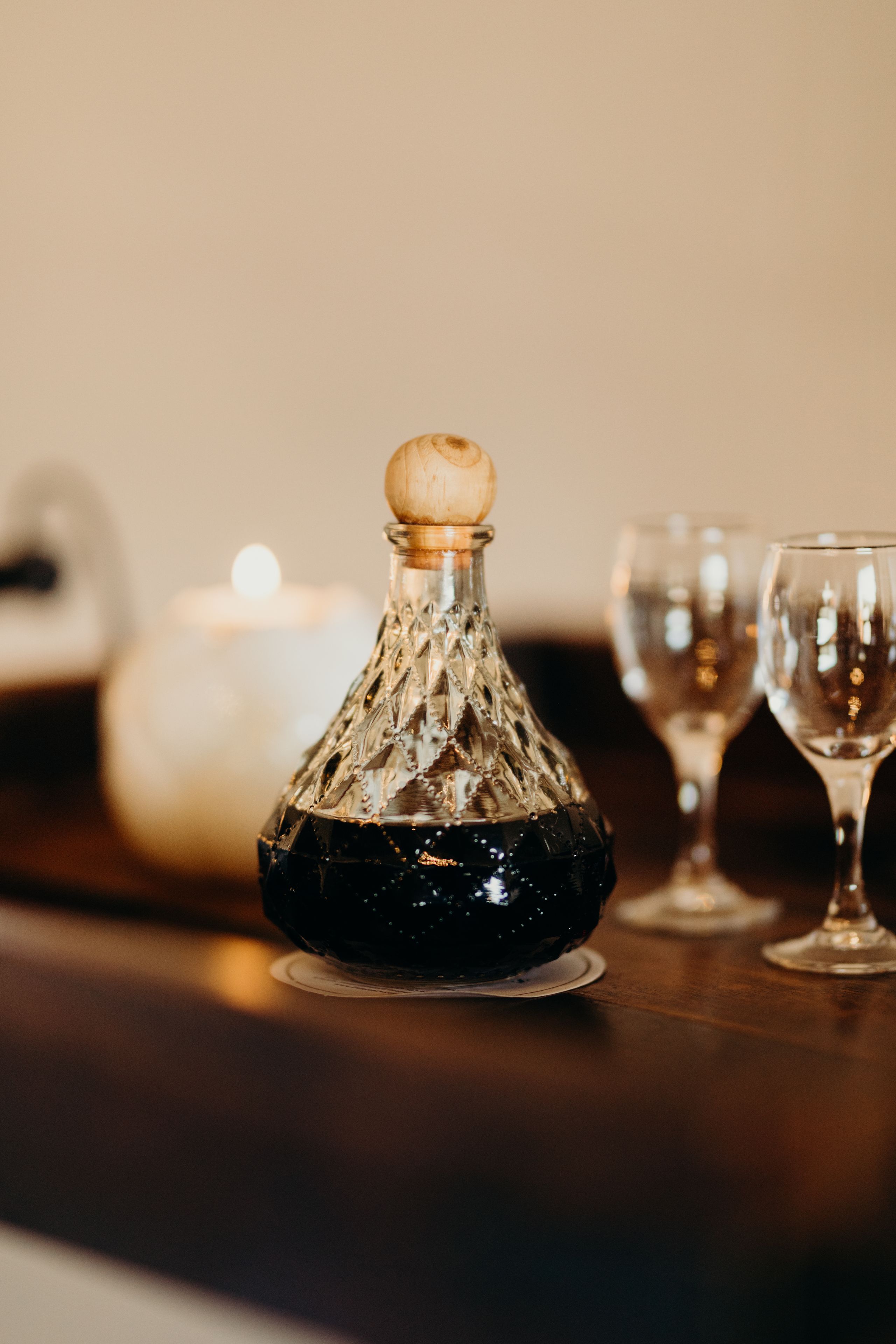 A glass decanter with a wooden stopper on a table.