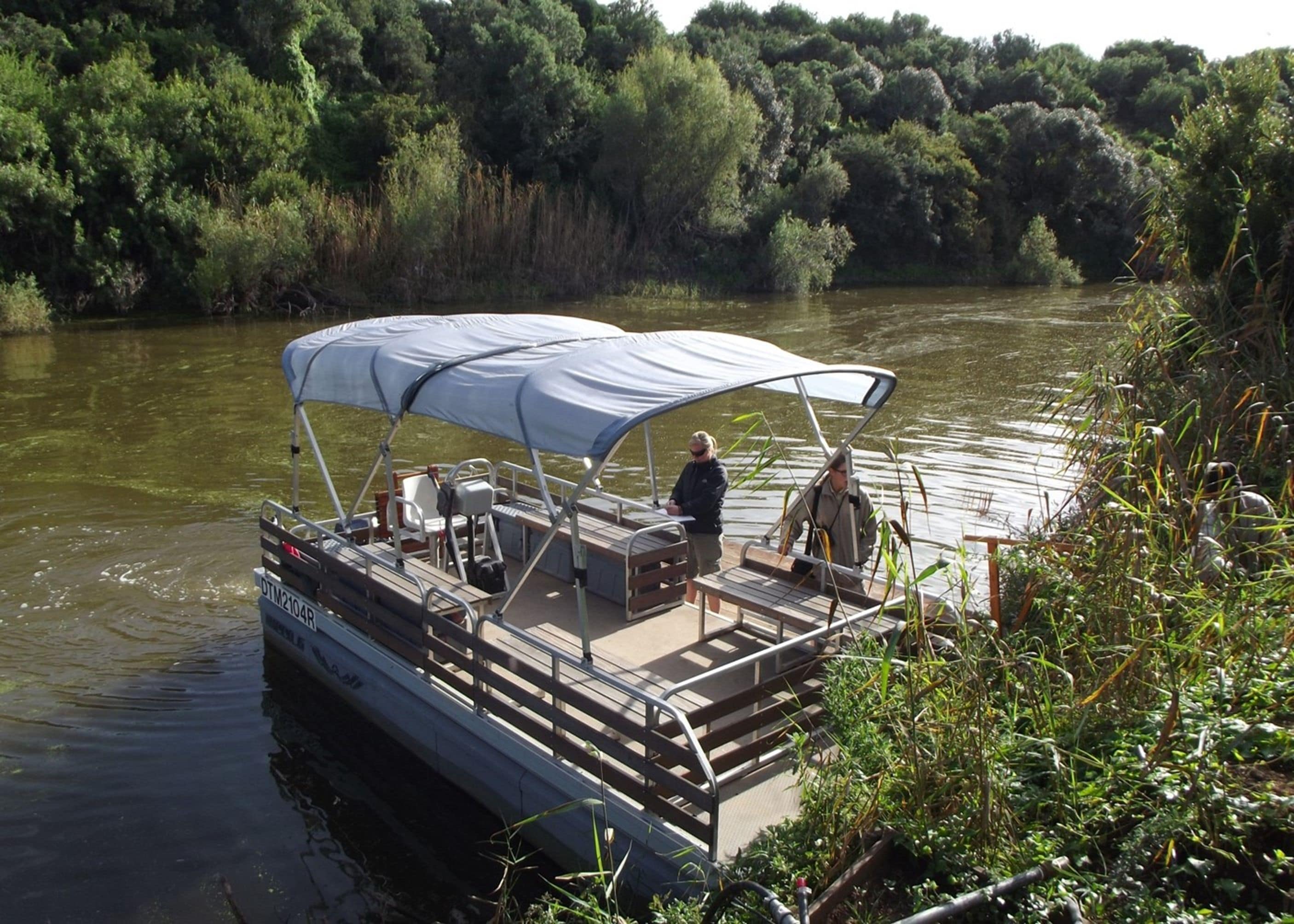 A boat with a covered seating area and a person standing at the bow.