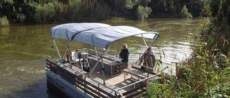 A boat with a covered seating area and a person standing at the bow.