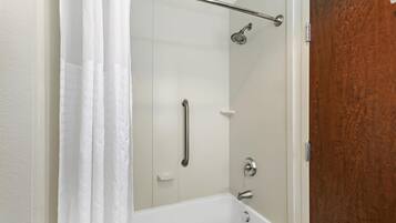A shower with a glass door, a handrail, and a showerhead.