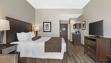Una habitación de hotel con cama, mesitas de noche, televisor, escritorio y una silla.
