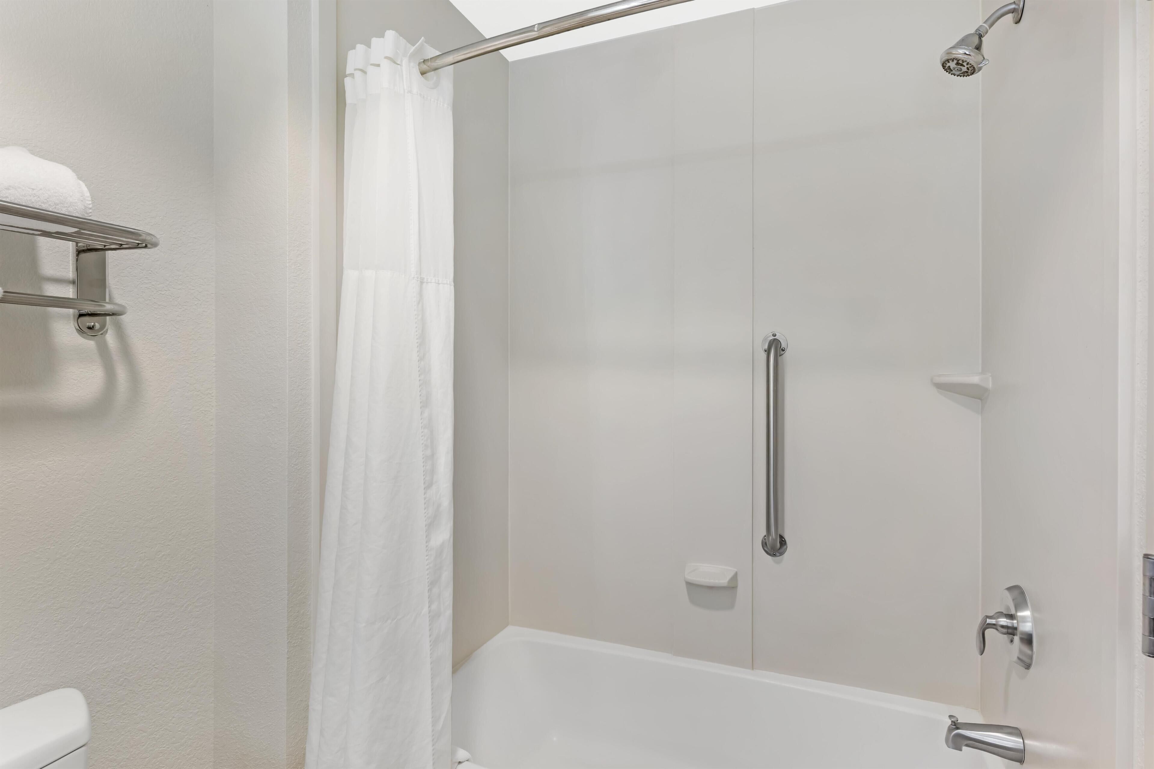 A bathroom with a shower, toilet, and a towel rack.