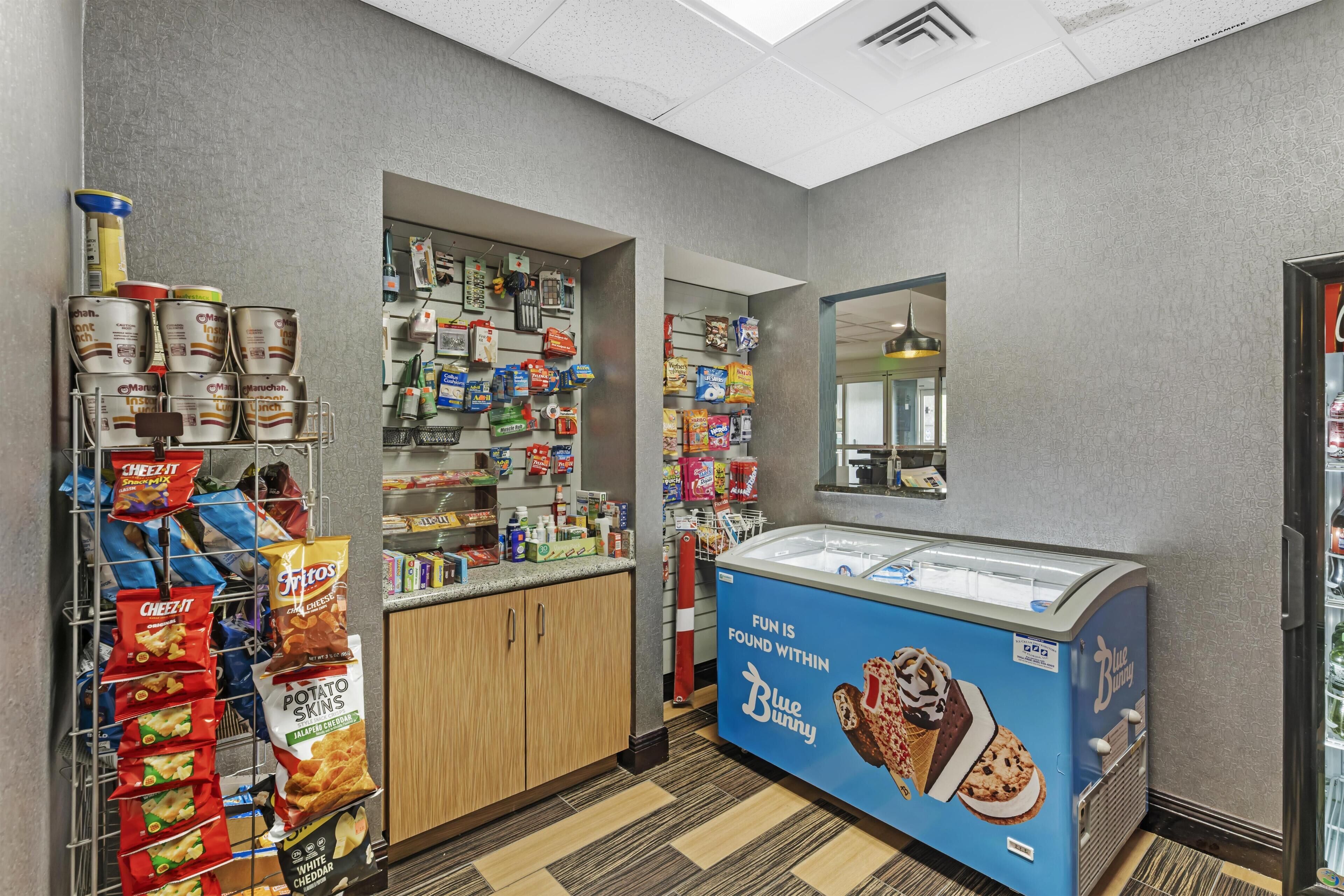A snack bar with a freezer, shelves of snacks, and a Blue Bunny ice cream display.