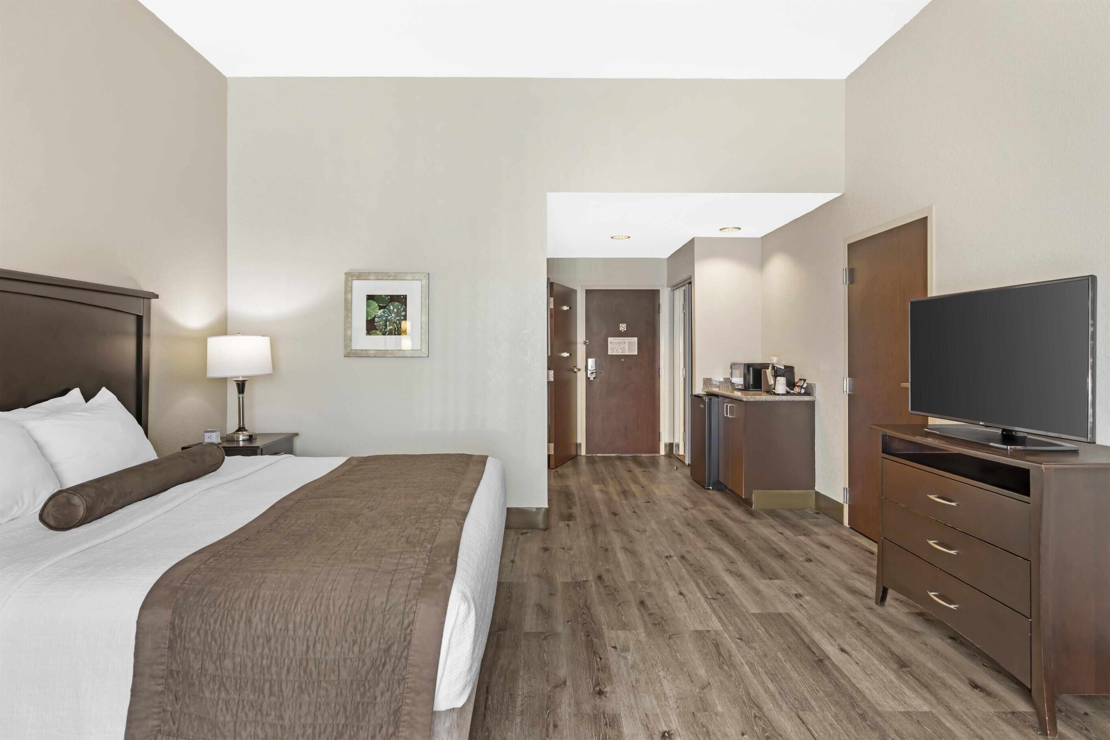 Ein Hotelzimmer mit einem Bett, einem Schreibtisch, einem Fernseher und einer Küchenzeile.