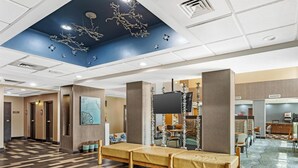 A hotel lobby with a check-in counter, seating area, and a reception desk.