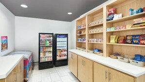 Un área limpia y bien organizada para snacks y bebidas, con dos dispensadores, estantes llenos de refrigerios y una encimera blanca.