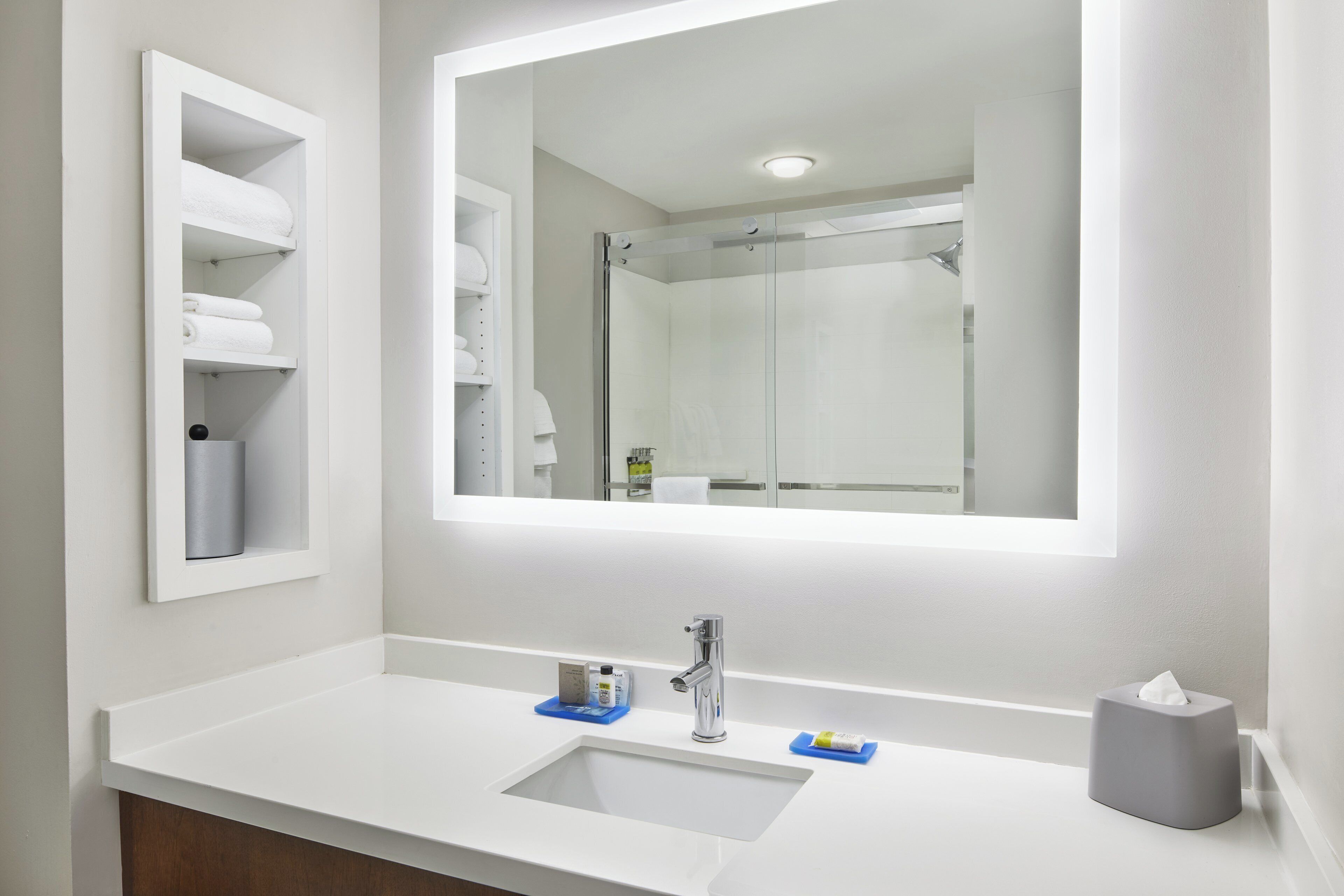 A bathroom with a white sink, a mirror, and a glass shower enclosure.