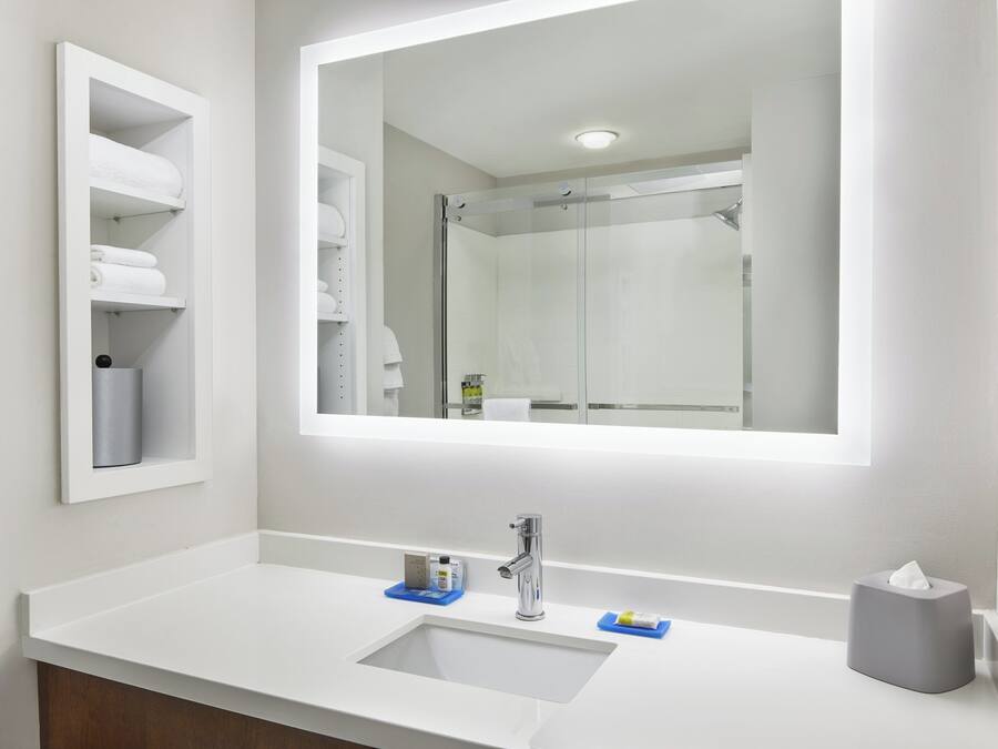 A bathroom with a white sink, a mirror, and a glass shower enclosure.