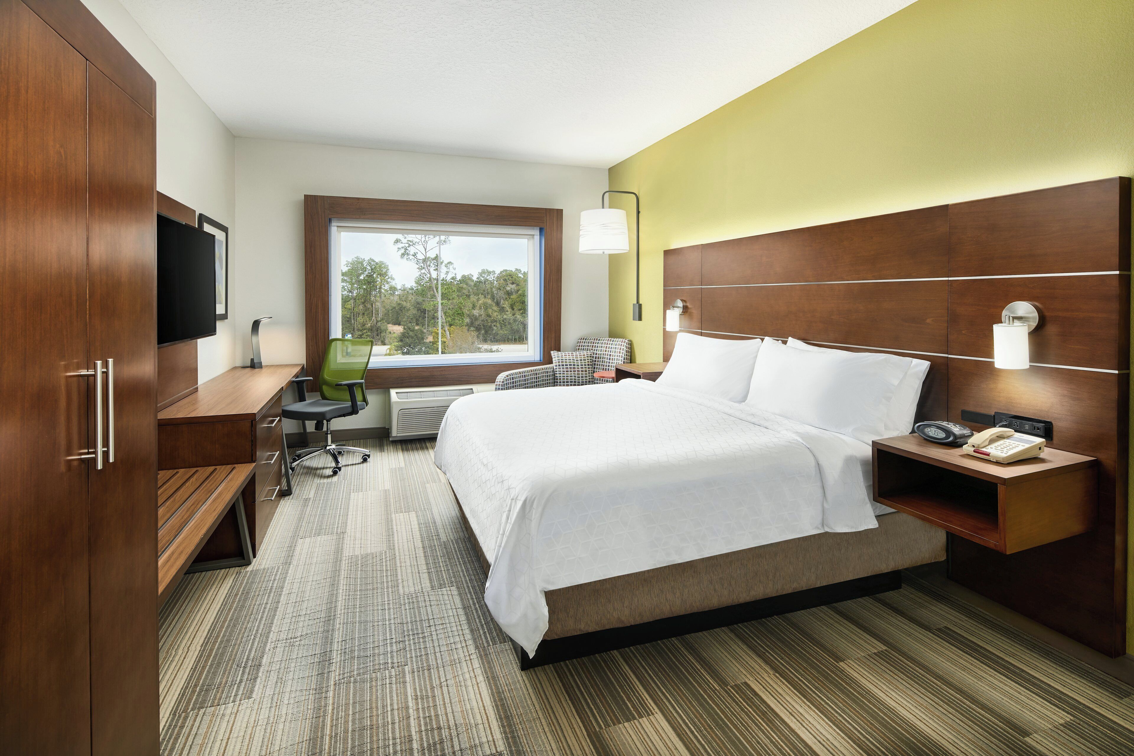 A hotel room with a bed, desk, chair, and a television.