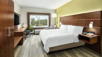 A hotel room with a bed, desk, chair, and a television.