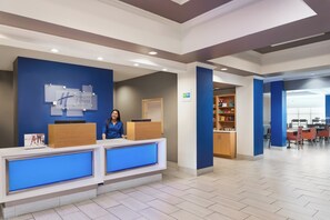 A hotel reception area with a reception desk, a counter, and a seating area with tables and chairs. - Holiday Inn Express Palatka Northwest by IHG (Palatka)