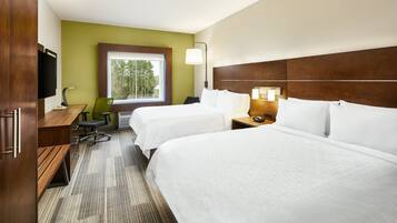 A hotel room with two beds, a desk, a chair, a TV, and a window with a view of trees.