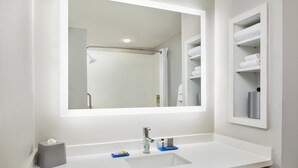Ein modernes Badezimmer mit großem Spiegel, weißem Waschbecken und Handtuchhalter.