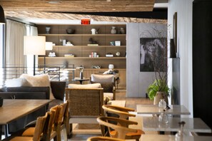 A modern interior with a sofa, chairs, a dining table, and a bookshelf. - The Lloyd Stamford, Tapestry Collection by Hilton (Stamford)