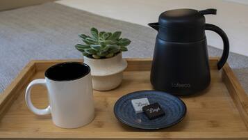 A tray with a white mug, a black coffee pot, a small potted plant, and two small black and white boxes labeled "Lloyd".