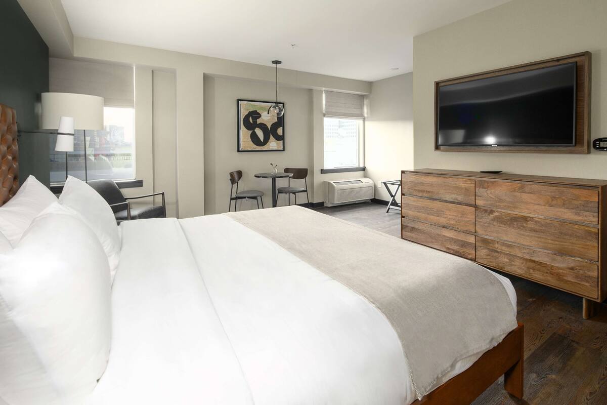 Une chambre d ’hôtel moderne dotée d’un grand lit, d’une télévision à écran plat, d’un bureau avec une chaise et d’une fenêtre offrant une vue agréable.