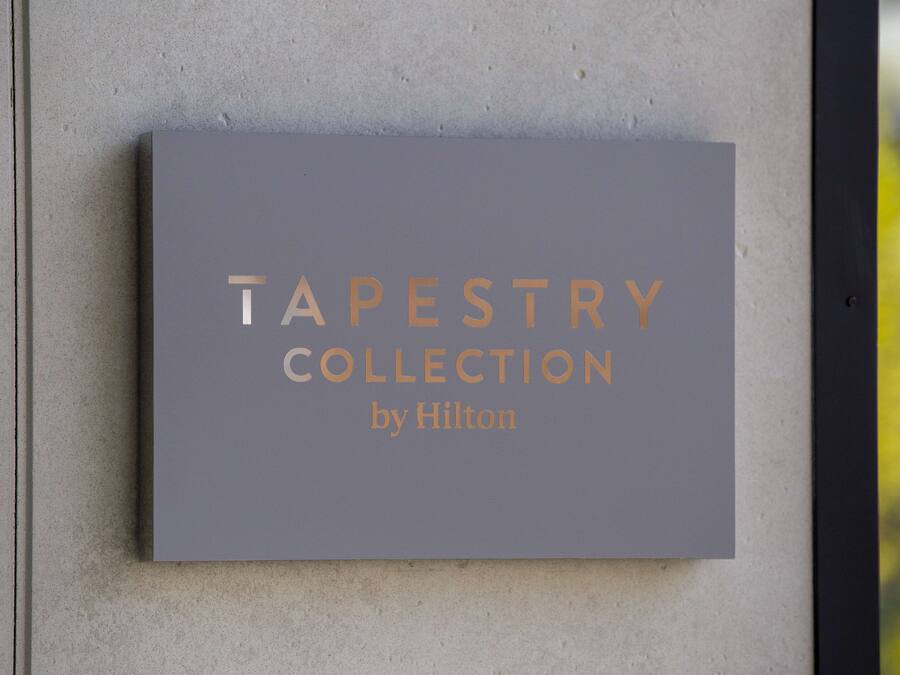 Een bord met de tekst 'TAPESTRY COLLECTION by Hilton' bevestigd aan een muur.