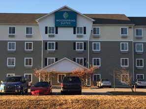 A multi-story hotel with a sign reading "Woodspring Suites." There are several cars parked in front, and the building has a symmetrical facade with evenly spaced windows. - WoodSpring Suites Chesapeake - Norfolk South (Chesapeake)