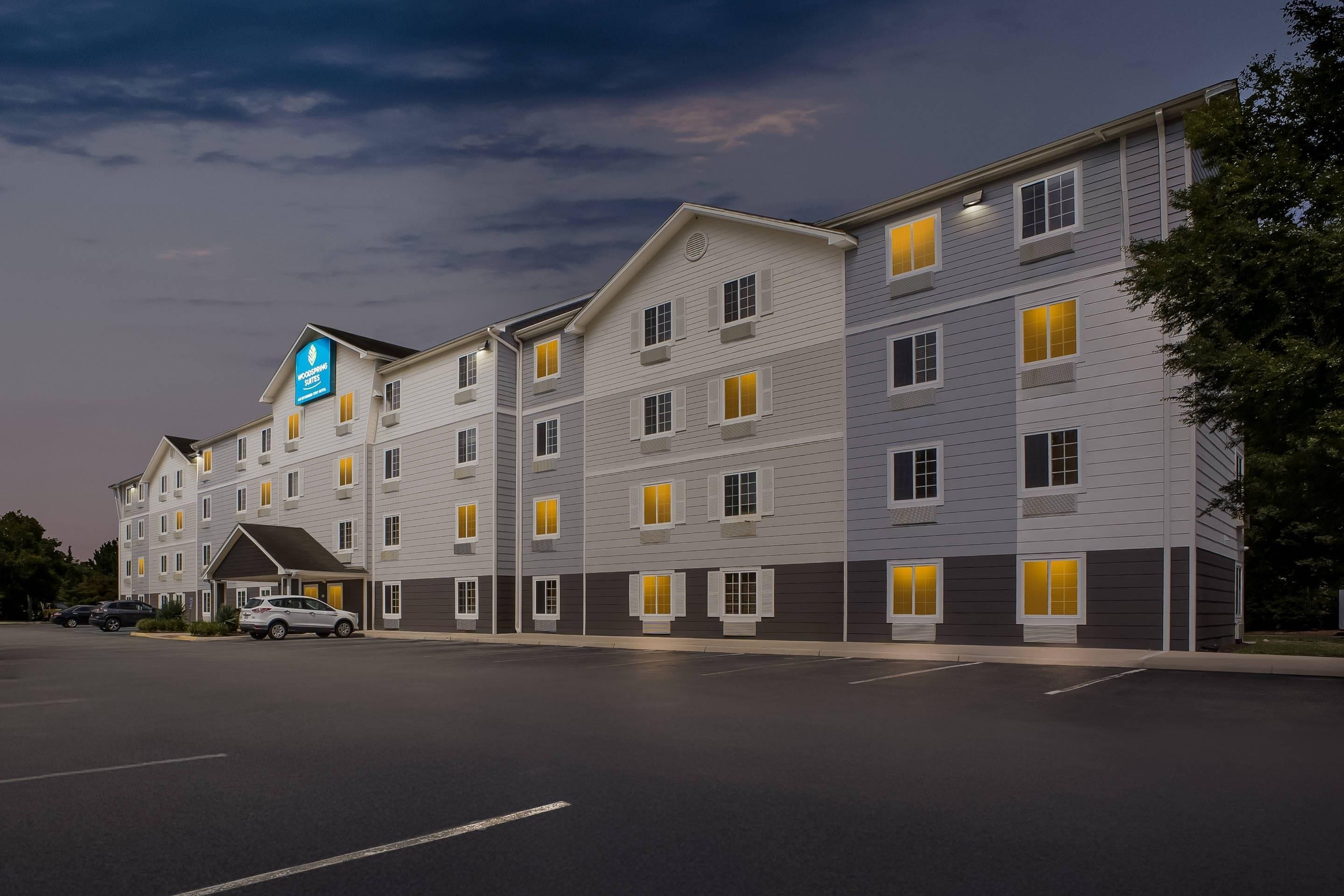 Um hotel com vários andares, teto plano e estacionamento em frente.