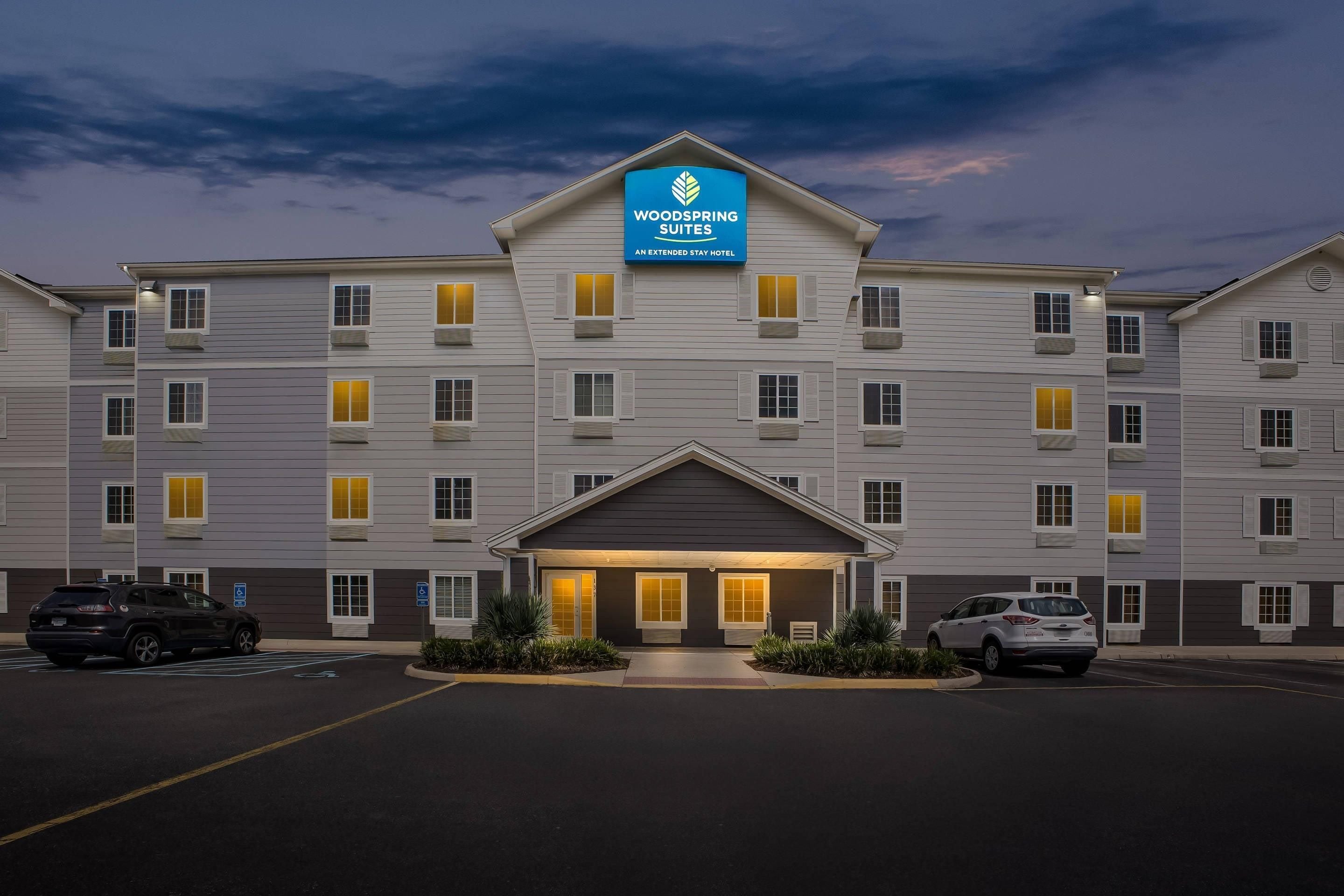 Un hotel de diverses plantes amb un cartell ben visible de WoodSpring Suites.
