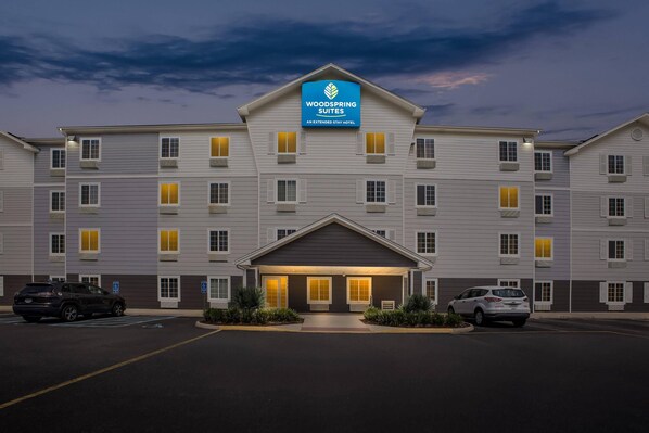 A multi-story hotel with a prominent sign for WoodSpring Suites.