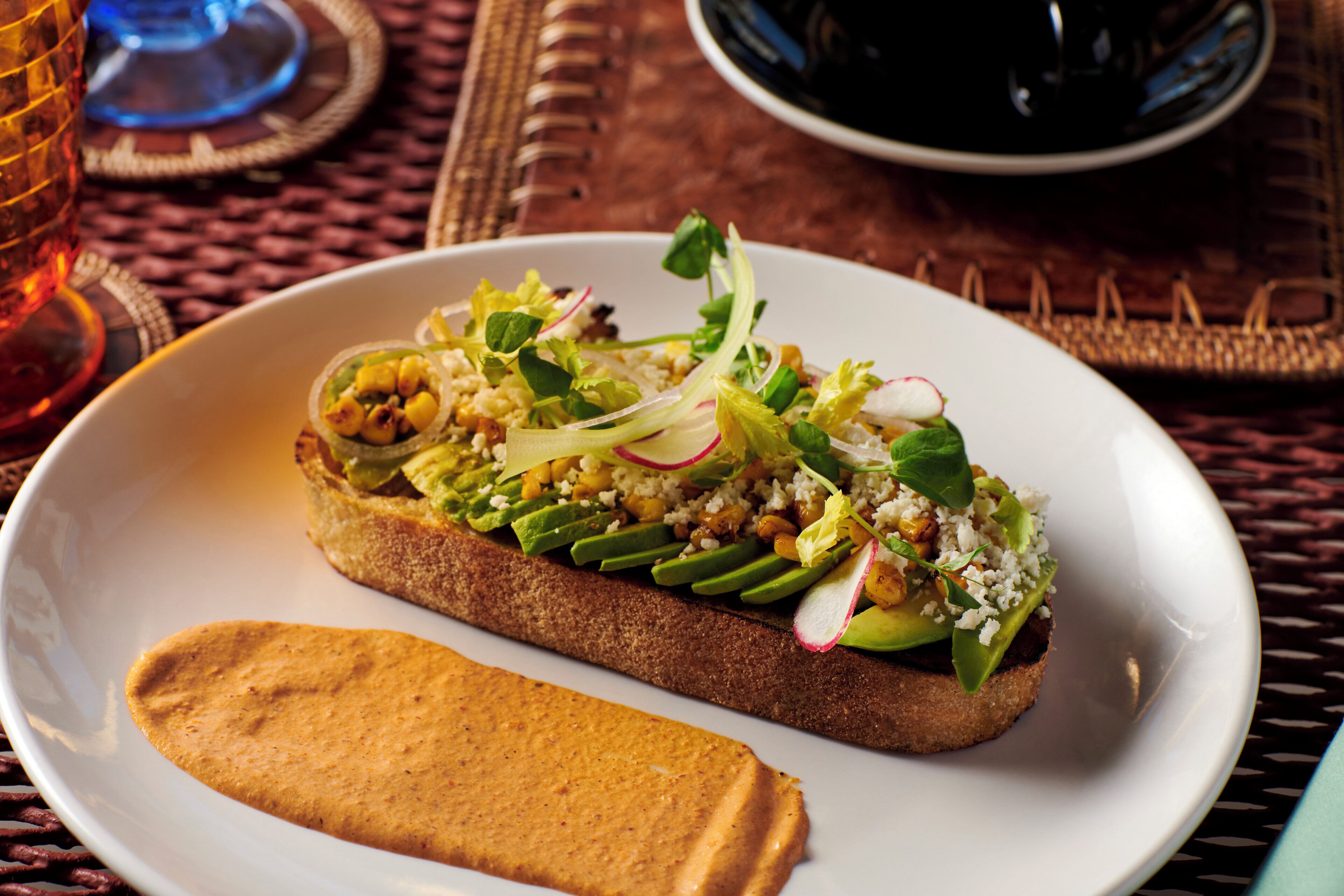 A plate with a sandwich and a side of sauce.