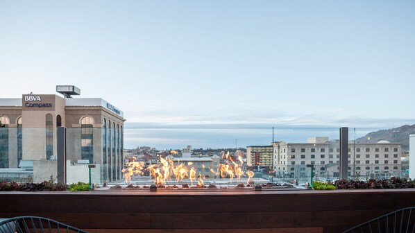 Une vue urbaine avec une fontaine dont les jets d’eau sont illuminés par des flammes, entourée de bâtiments, dont une succursale de la banque BBVA Compass.
