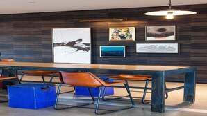 A modern dining area with a long wooden table, metal chairs, and artwork on the wall. - Hotel Indigo El Paso Downtown by IHG (El Paso)