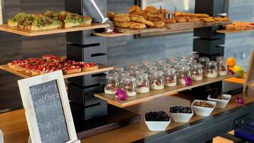 Un bufé con diversos alimentos, incluyendo pasteles, sándwiches y pequeños frascos de comida.