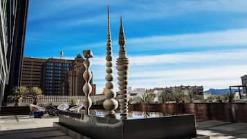 A modern sculpture with a reflective pool in an urban setting.