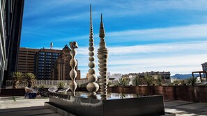 Una escultura moderna con un estanque reflectante en un entorno urbano.