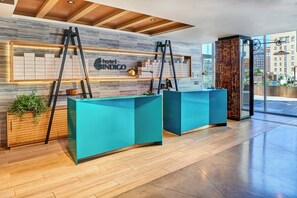 Hotellin vastaanottotiski, jonka yläpuolella on puinen katto ja jossa on kyltti, jossa lukee ”Hotel Indigo”.