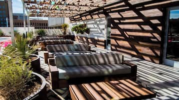 Un espacio de estar al aire libre con techo, bancos de madera y macetas.