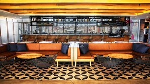 Un espace bar moderne avec un aménagement central comprenant des sièges, un comptoir et une vue sur la ville.
