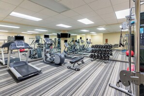 A gym with treadmills, elliptical machines, weight benches, and dumbbells.