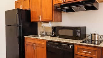 A kitchen with wooden cabinets, a black refrigerator, a microwave, a coffee maker, and a dishwasher.