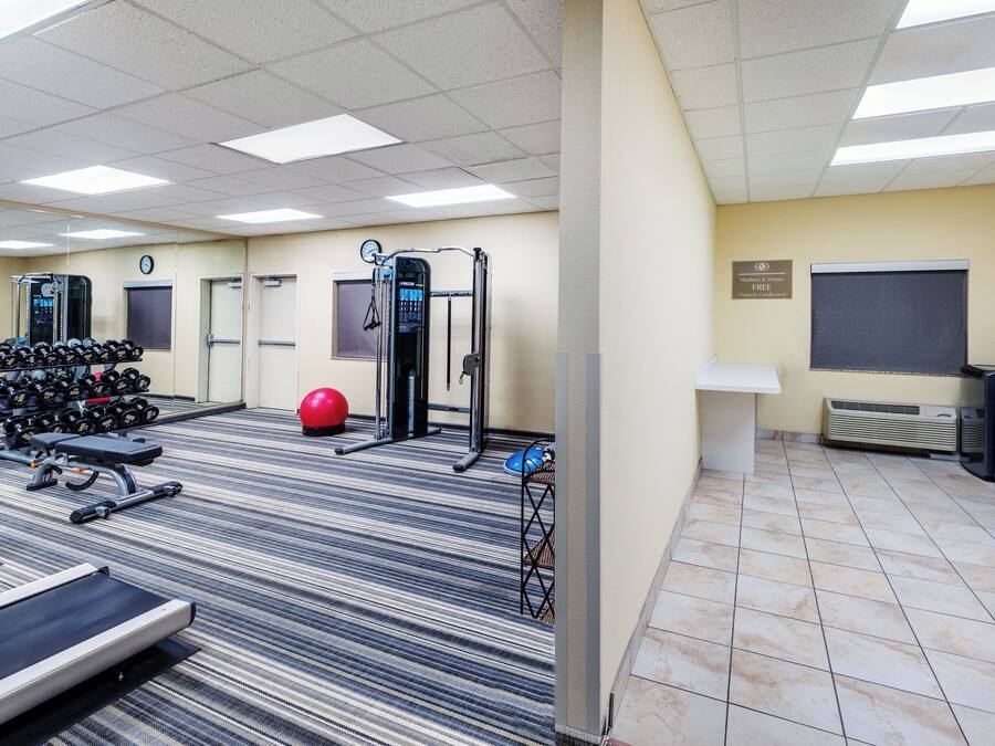 Un gimnasio con equipo de ejercicio, un reloj y un letrero que indica uso gratuito.