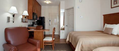Una habitación de hotel con cama, escritorio, silla y kitchenette.