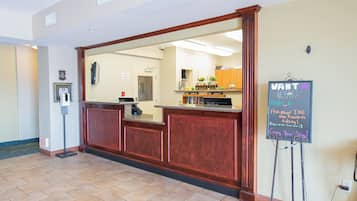 A reception area with a wooden reception desk, a chalkboard with messages, and a coffee machine.