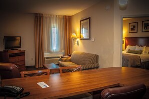 A hotel room with a wooden desk, a television, a sofa, and a bed. - Candlewood Suites New Iberia by IHG (New Iberia)