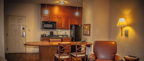 A compact living space with a kitchenette, a dining area, and a seating area with a leather chair.