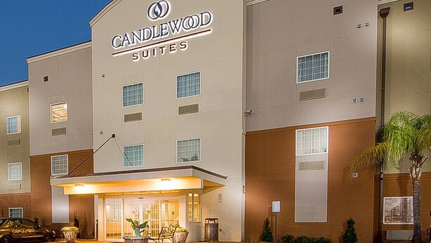 A hotel with a prominent "CANDLEWOOD SUITES" sign, a covered entrance, and a parking lot. - Candlewood Suites New Iberia by IHG (New Iberia)
