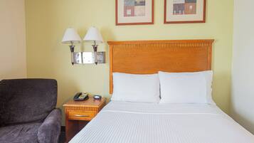 A hotel room with a bed, a nightstand, a telephone, a chair, and two wall-mounted lamps.