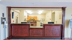 A reception area with a wooden reception desk, a bookshelf, and a counter. - Candlewood Suites New Iberia by IHG (New Iberia)