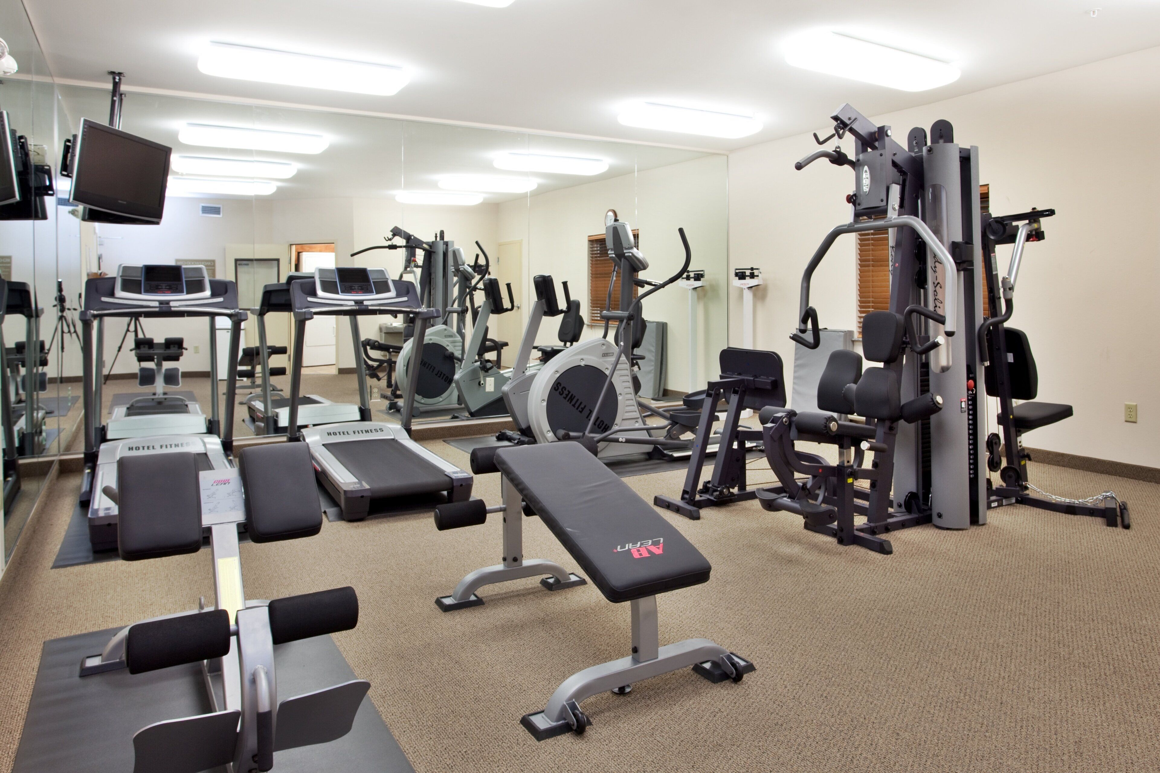 A hotel fitness center with various exercise equipment, including treadmills, elliptical machines, and weight stations.