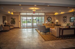 A lobby with a reception desk, seating area, and a large glass door leading outside. - Candlewood Suites New Iberia by IHG (New Iberia)