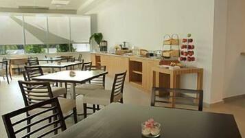 Una cocina moderna con zona de comedor, que incluye una isla central, sillas de madera y una pequeña mesa con un florero.